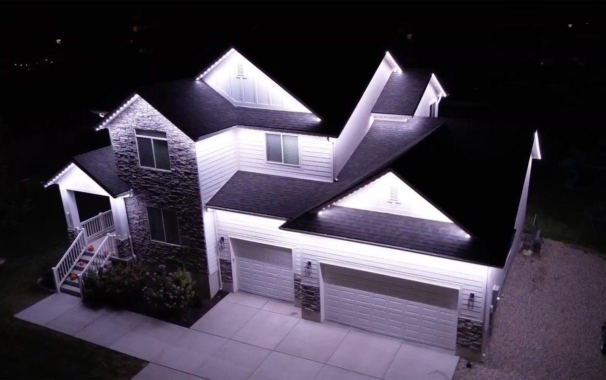 Aerial drone view of a Salt Lake City home with bright pure white permanent LED lighting along the entire roofline at night